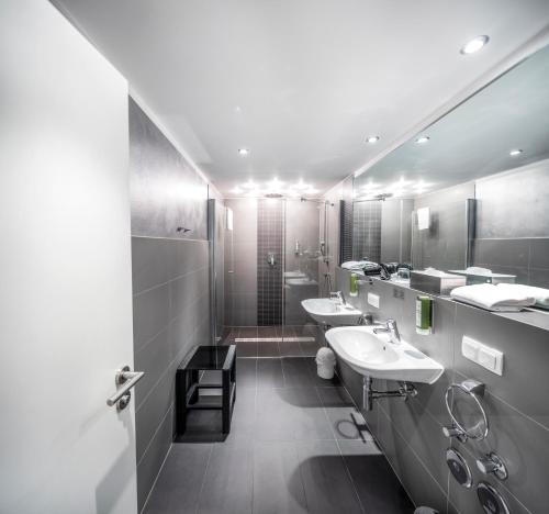 a bathroom with two sinks and two mirrors at BoardingWorld Heidelberg in Heidelberg
