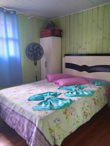 a bedroom with a bed with a flower blanket and a fan at Pousada Costa dos Canions in Cambará