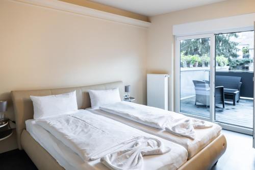 a bedroom with a bed with white sheets and a window at BoardingWorld Heidelberg in Heidelberg
