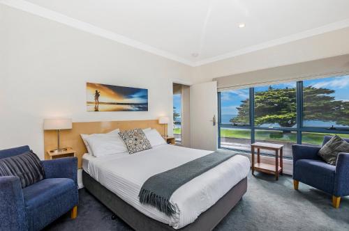 a bedroom with a bed and two blue chairs at Seascape Accommodation in Portland