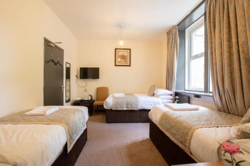 a hotel room with two beds and a window at Grainger House Hotel in Newcastle upon Tyne