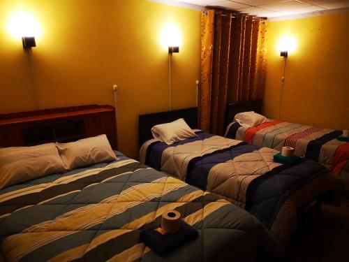 a hotel room with three beds in a room at Hostel Las Gardenias Ayacucho in Ayacucho