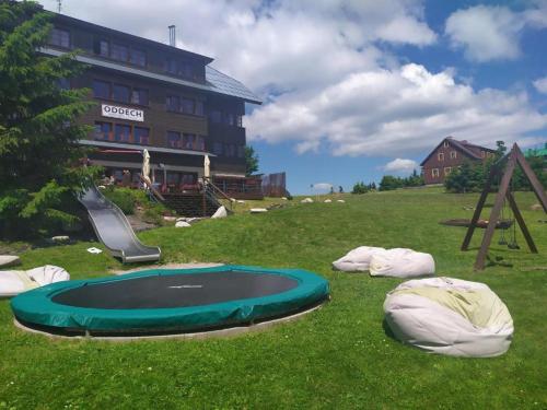 a playground with a trampoline in the grass next to a building at Hotel Oddech in Pec pod Sněžkou