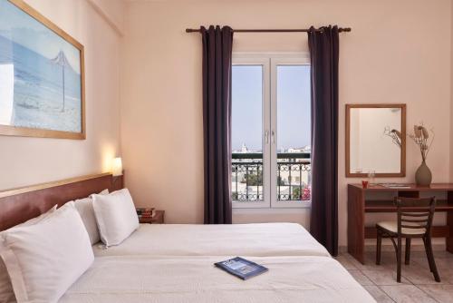 a bedroom with a bed and a desk and a window at Favie Suzanne in Tinos Town