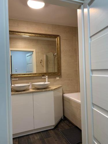 a bathroom with two sinks and a mirror and a tub at Apartament Jędrzejów in Jędrzejów