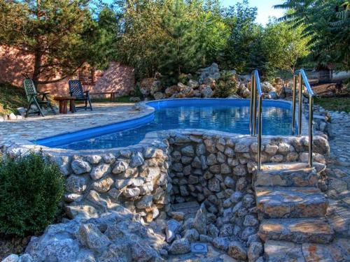 a swimming pool with a rock wall around it at Stara Vodenica in Klanjec