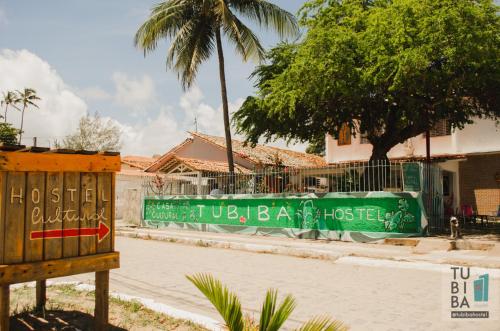 a street with a green fence and a palm tree at Tubiba Hostel in Tamandaré