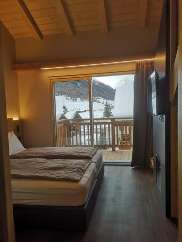 a bedroom with a bed and a large window at Garni Al Silvestri Vei in Livigno