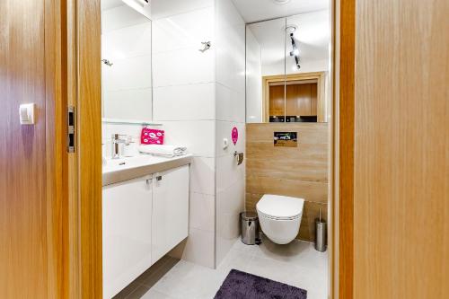 a white bathroom with a toilet and a sink at VacationClub – Seaside Apartament 505 in Kołobrzeg