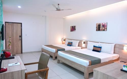 Habitación de hotel con 2 camas y mesa en M Stays en Chennai