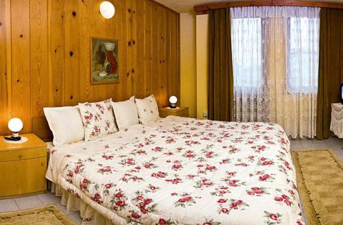 a bedroom with a large bed with red flowers on it at Hotel Vesta in Kazanlŭk