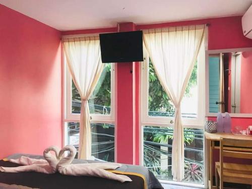 a bedroom with a pink wall with windows and a bed at Sea Shell Hut in Phi Phi Don