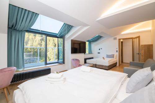 a bedroom with a large white bed and a living room at Erlebachova Bouda, hotel - Resort Svatý František in Špindlerův Mlýn