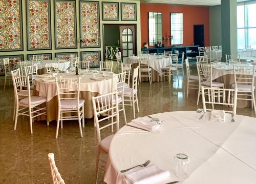 a dining room with tables and chairs with white tablecloths at Don Polvorón in Estepa