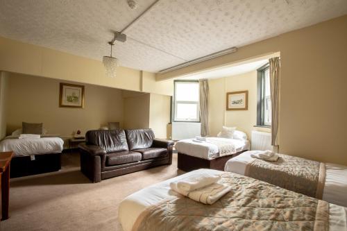 a hotel room with two beds and a couch at Grainger House Hotel in Newcastle upon Tyne