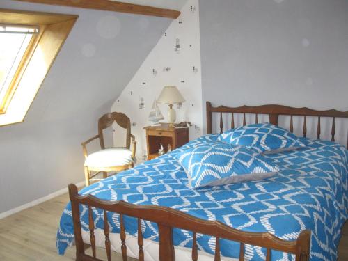 Schlafzimmer mit einem Bett mit einer blauen und weißen Bettdecke in der Unterkunft Le Repos des Crins Noirs in Esson
