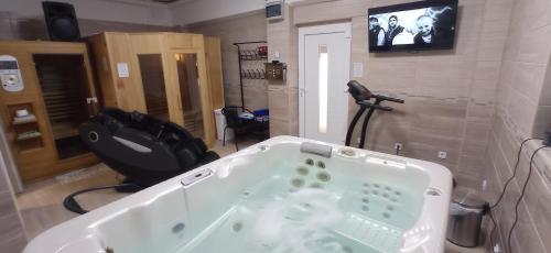a bathroom with a bath tub and a tv at Robitel Wellness Vendégház Veszprém-Gyulafirátót in Veszprém