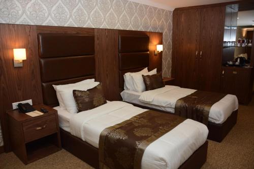 a hotel room with two beds and a night stand at Ankawa Royal Hotel & Spa in Erbil