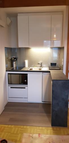 a kitchen with white cabinets and a sink at Bord de plage, thalasso et vue mer ! in Cabourg