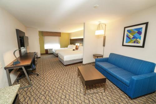 スプリングフィールドにあるHoliday Inn Express and Suites Springfield Medical District, an IHG Hotelの青いソファとベッドが備わるホテルルームです。