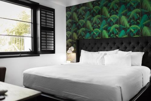 a bedroom with a large bed with a green wall at SoBro Guest House by Black Swan in Nashville