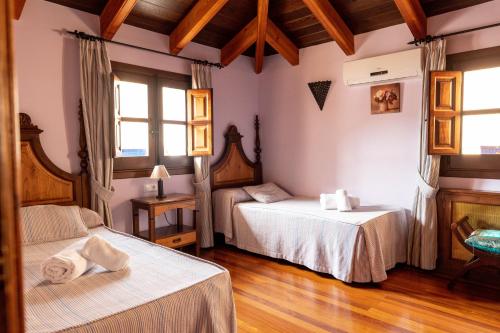 two beds in a room with wooden floors and windows at La Colegiata De Ronda in Ronda