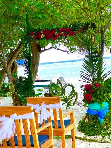 two chairs sitting on a beach with flowers and the ocean at RISING SUN BEACH VIEW in Thinadhoo