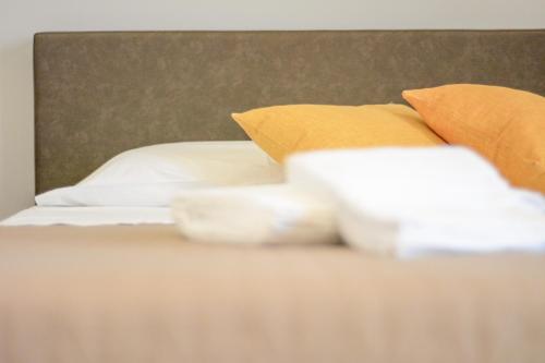 a bed with orange and white pillows on it at Nnakkara Guest House in Santo Stefano di Camastra