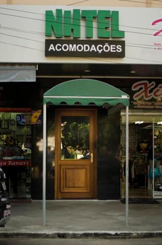a store with a green umbrella in front of a door at Nhtel Acomodações in Novo Hamburgo
