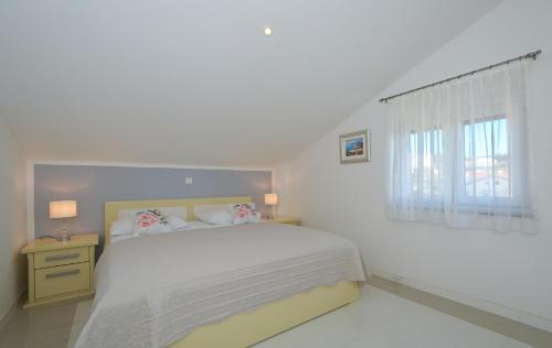 a white bedroom with a bed and a window at Villa Klaudia in Trogir