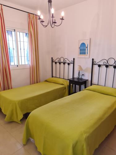 2 camas en una habitación con sábanas amarillas en APARTAMENTO BONITO EN PINAL DEL MAR NERJA en Nerja