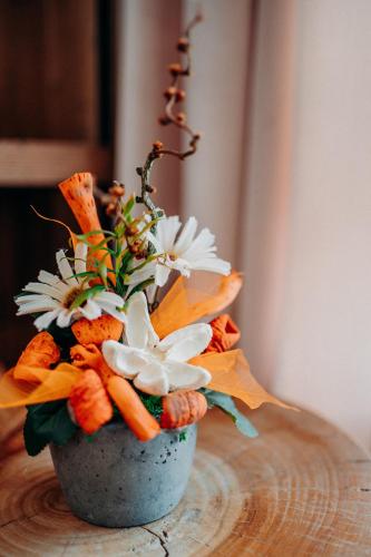 a vase filled with flowers and carrots on a table at JOHAN HOTEL in Zlín