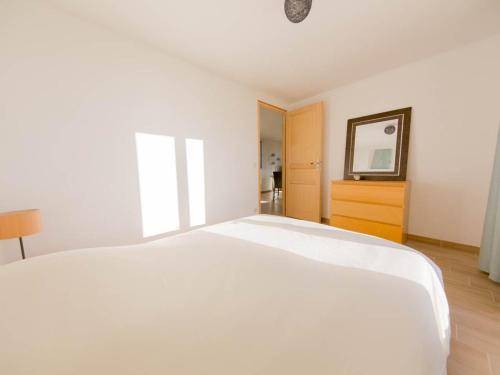 a white bedroom with a bed and a mirror at La Tour de la Conterie in Beaumont-Village