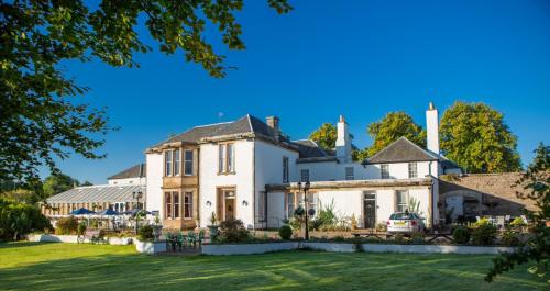 an exterior view of a large white house with a yard at Maitlandfield House Hotel in Haddington