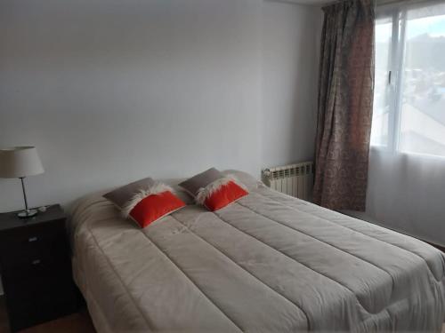 um quarto com uma cama grande e 2 almofadas vermelhas em Vista Ushuaia em Ushuaia