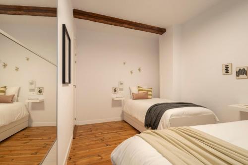 パンプローナにあるPrecioso apartamento recién reformado pleno centroの白い壁とウッドフロアの客室で、ベッド2台が備わります。