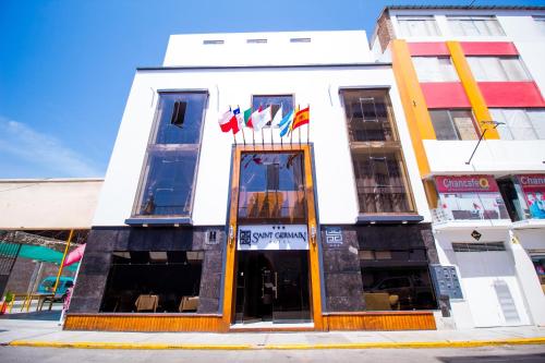 a white building with flags in front of it at Saint Germain Hotel in Trujillo