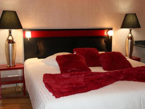 ein Bett mit roten Kissen und zwei Lampen in der Unterkunft Marinha Hotel in Gentilly