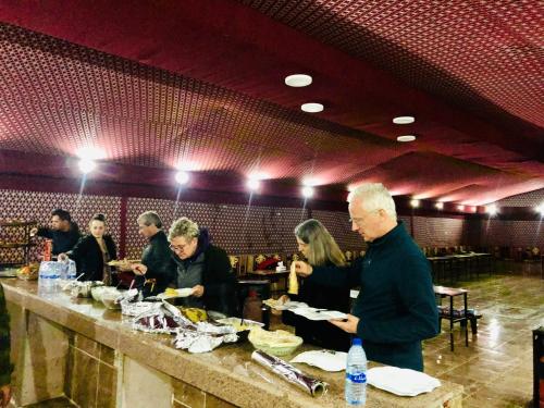 a group of people standing at a counter in a restaurant at Shakria Bedouin Life Camp in Wadi Rum