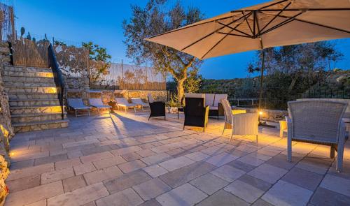 eine Terrasse mit einem Sonnenschirm, Tischen und Stühlen in der Unterkunft Villa Vanessa con Piscina Privata - Castro in Castro di Lecce