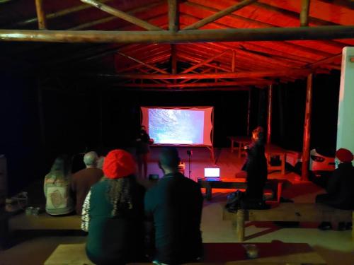 a group of people watching a presentation on a screen at Ecovila Coração da Mata in Brumadinho