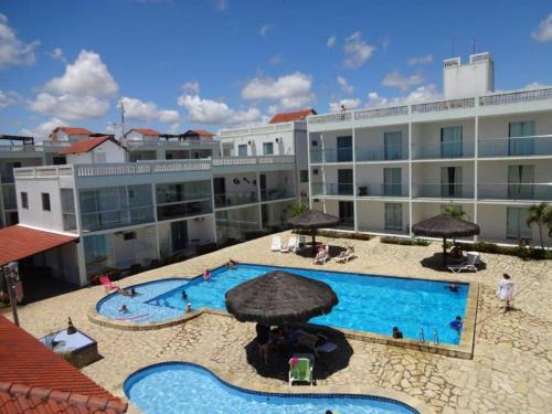 a large pool with umbrellas in front of a building at Apto Praia do Amor 2 quatos in Conde