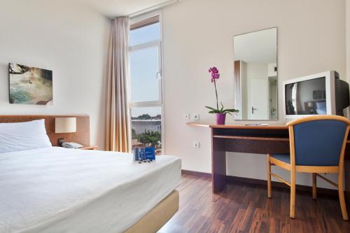 a hotel room with a bed and a desk and a mirror at Crisol Quality Reus in Reus