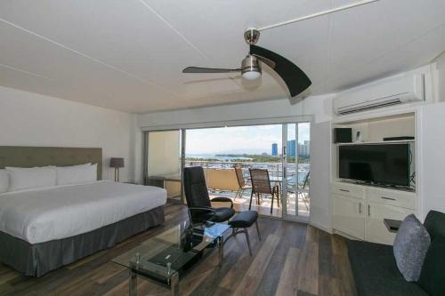 a bedroom with a bed and a television and a balcony at Ilikai Tower 1033 Yacht Harbor View 1BR in Honolulu