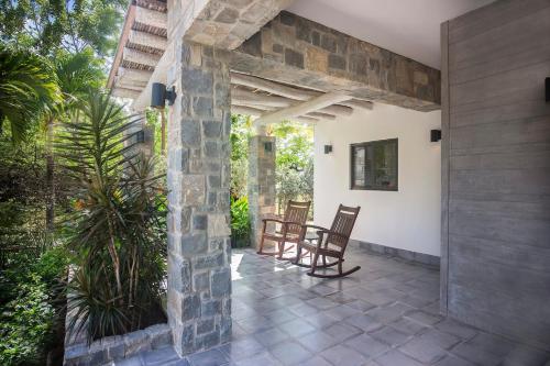 a patio with two chairs and a stone wall at Iguana Beach House in Iguana