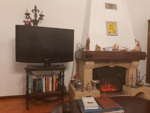 a living room with a television and a fireplace at Lavra Beach House in Lavra