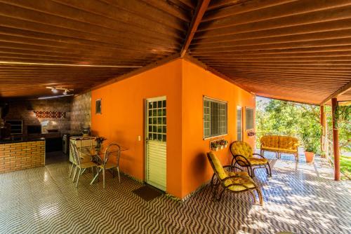 una habitación con una casa naranja con sillas y mesa en Pousada e Restaurante Maria das Flores, en Três Marias