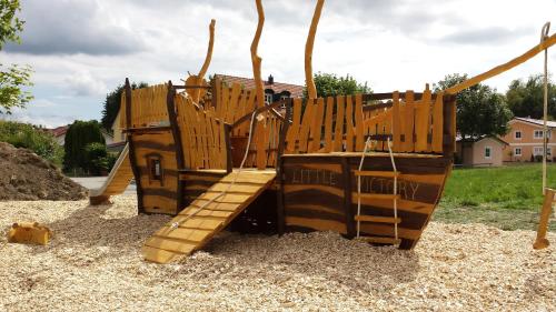 a playground with a wooden play structure in gravel at Hotel Nummerhof in Erding