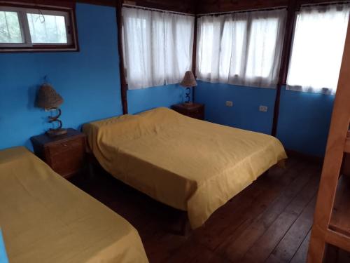 2 camas en una habitación con paredes y ventanas azules en Cabañas La Caballeriza San Lorenzo en Salta