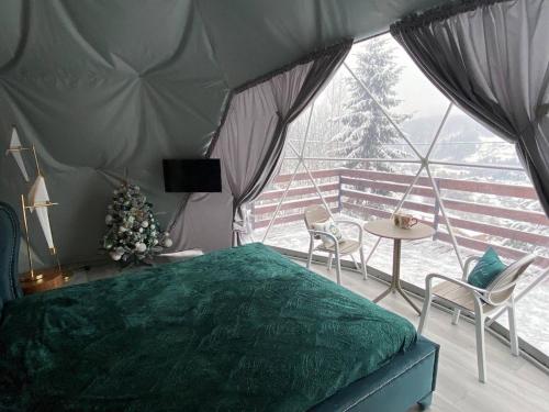 Schlafzimmer mit einem grünen Bett, einem Tisch und Stühlen in der Unterkunft Karpatski Dzherela in Jaremtsche
